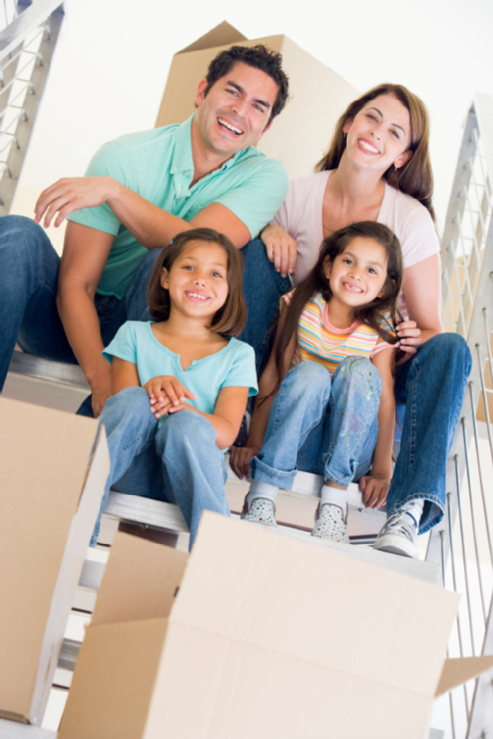 Family sitting on staircase with boxes in new home smiling